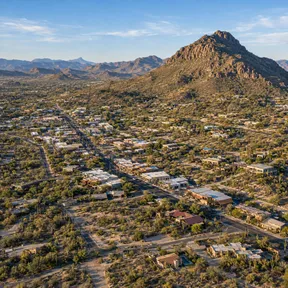 Aerial drone view of downtown Cave Creek, Arizona, with a rocky desert peak rising above the town's main street.