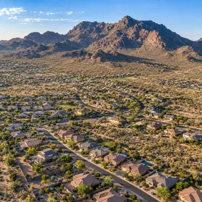 Aerial drone view of a new-build neighborhood in San Tan Valley, Arizona, with mountains rising behind it.