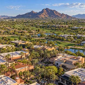 Aerial drone view of a resort and golf course district in Scottsdale, Arizona, with Camelback Mountain in the background.