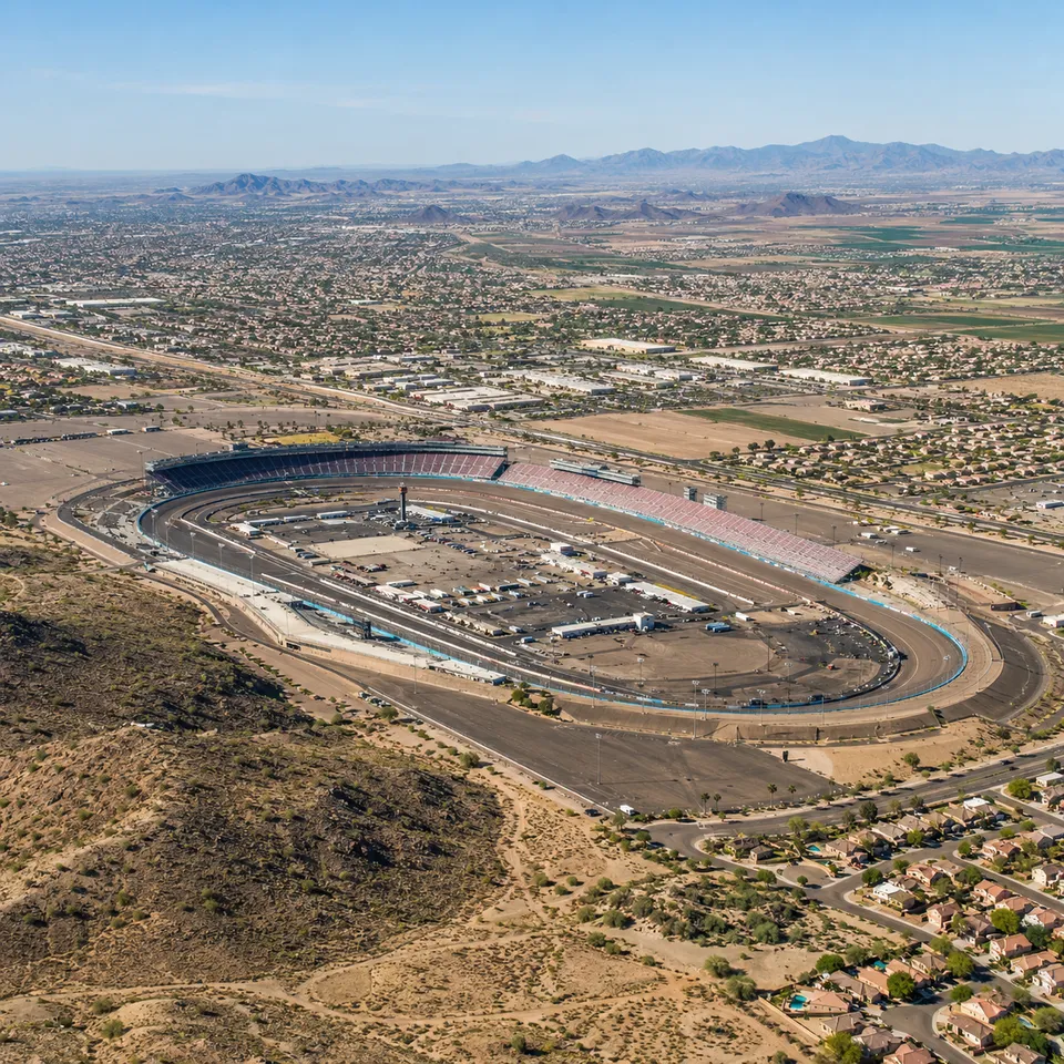 Aerial drone view of Phoenix Raceway's oval track in Avondale, Arizona, surrounded by desert and West Valley suburbs.