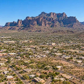 Aerial drone view of Apache Junction, Arizona, with the jagged Superstition Mountains rising behind the town.