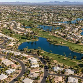Aerial drone view of Sun City, Arizona's circular retirement community streets wrapped around golf course lakes.