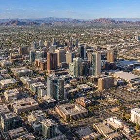 Aerial drone view of the downtown Phoenix, Arizona skyline with mountains in the background.